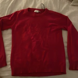 Röd/rödrosa tröja från Vila - Säljer en snygg röd/rödrosa tröja från Vila. Den har en klassisk rund halsringning och långa ärmar. Perfekt för att hålla sig varm under kyligare dagar. Tröjan är enkel och stilren, vilket gör den lätt att matcha med olika outfits.