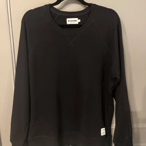 Svart tröja från Resteröds - Svart tröja från Resteröds. Tröjan har långa ärmar och en rund halsringning. Den har en liten etikett nertill som ger en extra touch.