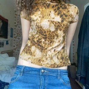 Leopardmönstrad topp - Säljer en cool leopardmönstrad topp med korta ärmar och polokrage. Toppen har en tight passform. Den är gjord i ett mjukt och stretchigt material som sitter bekvämt.