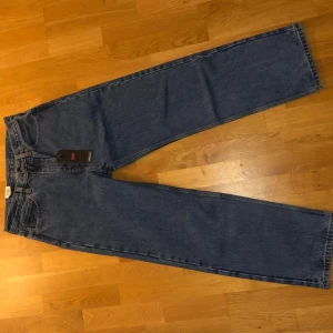 Blå baggy jeans från Levi's - Säljer ett par klassiska blå baggy jeans från Levi's. De har en avslappnad passform med hög midja och är tillverkade i slitstarkt denim. Perfekta för en casual look. Märkeslappen och Levi's logga syns tydligt på baksidan.