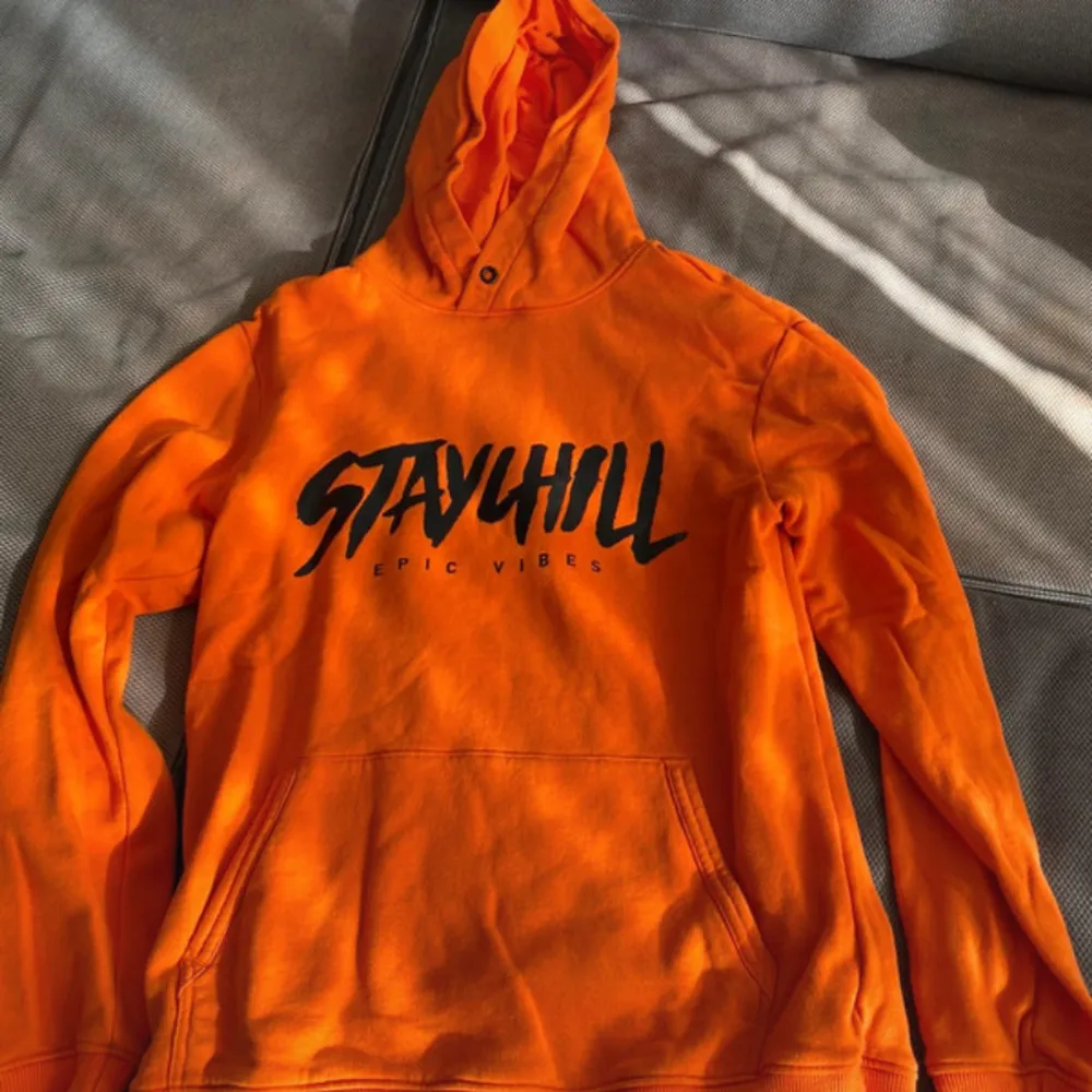 Säljer en cool orange hoodie från Stayhill med texten 'EPIC VIBES' tryckt på framsidan. Tröjan har en klassisk känguruficka och en justerbar huva. Perfekt för en avslappnad stil.. Neuletakit & Villapaidat.