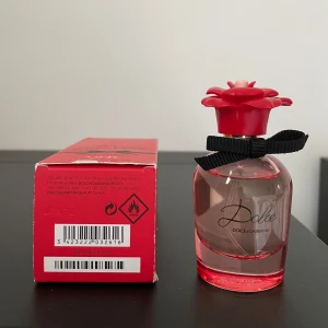 Dolce & Gabbana Dolce Rose Parfym - Parfym användes ett fåtal gånger (25/30 ml kvar). Pudełko jest trochę obtarte (zobacz zdjęcie). Pris nu för produkten till 985 sek. Säljer en elegant Dolce & Gabbana Dolce Rose parfym. Flaskan är genomskinlig med en röd bas och ett vackert rött blomlock. Den har en svart rosett runt halsen. Förpackningen är röd och matchar flaskans design.