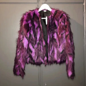 Lila och svart pälsjacka - Helt ny med prislapp kvar.Tyvärr har jag inte haft tillfälle för att använda den.  Har dragkedja och två fickor är en storlek 158/164 men passar mig som är small/ liten medium. Nypris 349kr.