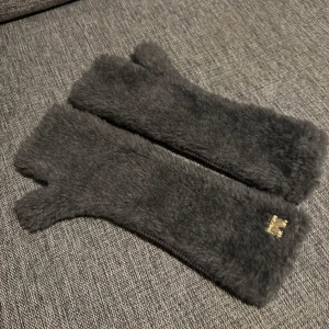 Ullvantar från Max Mara - Snygga svarta handskar från Max Mara i ett mjukt och fluffigt material. De har en elegant design med en liten gulddetalj. Utsidan : 44% Ull 44% Alpacka  Insidan: 100% Ull