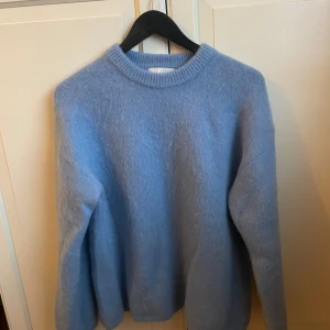 Ljusblå mohair tröja från H&M Edition - Säljer en mysig ljusblå stickad tröja från H&M Edition i Mohair-blandning. Tröjan har en rund halsringning och långa ärmar, perfekt för kyligare dagar. Den är i en mjuk och fluffig kvalitet som ger en skön känsla. Inga defekter, fläckar eller noppriga partier, som ny! Nypris 699
