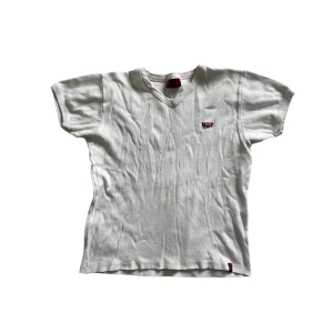 Vit t-shirt från Levi's - Klassisk vit t-shirt från Levi's med v-ringning och korta ärmar. Perfekt för en avslappnad stil.