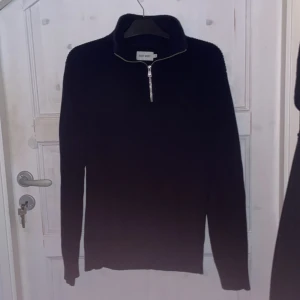 Navy blå stickad tröja från East West, Storlek M. Ny skick använd fåtal gånger. - Snygg svart tröja från Gant med dragkedja vid halsen. Perfekt för kyligare dagar med sin stilrena design och långa ärmar. Passar både till vardags och mer uppklädda tillfällen.