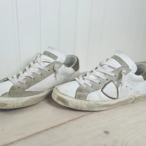 Vita sneakers från Philippe Model - Snygga vita sneakers från Philippe Model med grå detaljer och snörning. Skorna har en klassisk design med en bekväm sula och är perfekta för en avslappnad stil.