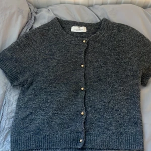 Grå kofta från H&M - Mysig grå kofta från H&M med korta ärmar och knappar framtill. Helt oanvänd, storlek 158/164❤️ nypris 299❤️