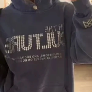 Mörkblå hoodie med text - Säljer en mörkblå hoodie med texten 'FOR THE CULTURE' i glittriga bokstäver på framsidan. Hoodien har en klassisk känguruficka och en liten logga på ärmen.