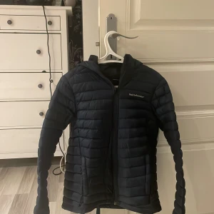 Svart dunjacka från Peak Performance - Säljer en svart dunjacka från Peak Performance. Jackan har en quiltad design med dragkedja och huva. Perfekt för kyligare väder och har en stilren look. Skulle säga att den passar 155-170 nypris 2299
