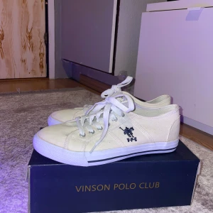 Vita sneakers från Vinson Polo Club - Säljer ett par vita sneakers från Vinson Polo Club med snörning och en broderad logotyp på sidan. Skorna har en klassisk design med låg profil och vit sula. Perfekta för en stilren look.