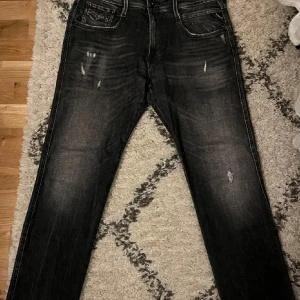 Svarta jeansbyxor från Replay - Snygga svarta jeansbyxor från Replay, modell Anbass. De har en klassisk femficksdesign med diskreta slitningar för en cool look. Perfekta för en avslappnad stil.