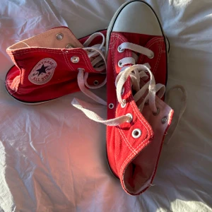 Röda sneakers från Converse - Snygga röda Converse All Star sneakers med vit tåhätta och snörning. Perfekta för en avslappnad stil med en klassisk touch. De har en ikonisk logga på sidan och är bekväma för daglig användning. Stl 38-40!
