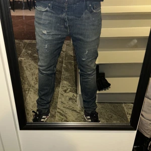 jeans med slitningar - Snygga blå jeans med slitningar för en trendig look. Personen på bilden är ca 180 cm lång och väger 70 kg. Jeansen är Perfekta för en avslappnad stil. Tveka inte på att kontakta mig vid minsta fundering🙌