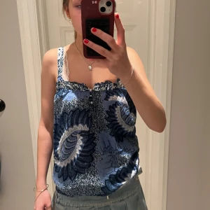 Sommar blå mönstrad linnetopp - Säljer en blå linnetopp med ett stort blommigt mönster i mörkblått och vitt. Toppen har smala axelband och en lös passform, perfekt för varma dagar. Perfekta sommarn toppen! ☀️Köpte från Zalando men märket NEXT