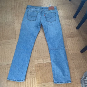 Levis 511 jeans i ljusblå denim - Snygga Levis 511 jeans i ljusblå denim. De har en klassisk femficksdesign och en bekväm passform. Perfekta för en avslappnad stil.