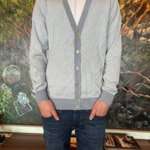 Ljusblå kofta från Stenströms - Säljer en stilren ljusblå kofta från Stenströms med knappar framtill. Koftan har en v-ringad design. Perfekt för en elegant och avslappnad outfit. Modellen på bilden är 175 cm lång och väger 58 kg. Nypris 2300kr