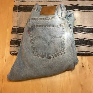 Levis jeans i ljusblå denim 501 - Säljer ett par klassiska Levis jeans i ljusblå denim. De har en straight passform och är perfekta för en avslappnad stil. Jeansen har den ikoniska Levis-lappen på baksidan och fem fickor.