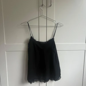 Svart linne från Zara  - Säljer ett stilrent svart linne från Zara med tunna axelband och spetsdetaljer vid halsringningen och nederkanten. Perfekt för fest men också till vardags💫💕Säljer för 120kr + frakt