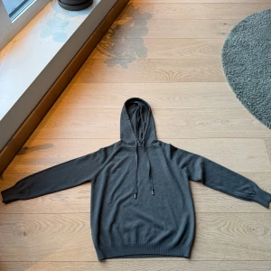 Grön hoodie marinoull - Säljer en stilren grön hoodie med dragsko i huvan. Tröjan är långärmad och har en mjuk, stickad känsla. Perfekt för en avslappnad look.