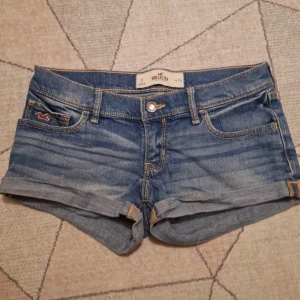 Low waist Hollister shorts - Ett par ljus blå Hollister shorts i storlek w24. De har ett snyggt motiv på fickorna och de är low waist. Själv har jag ändast använt den ett par gånger, men de är köpta secondhand. De är I mycket bra skick skulle jag säga och har inga skador. Säljer dem pga att de är för små för mig✨️