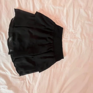 Svart kjol från ONLY - Snygg svart kjol från ONLY med elastisk midja för en bekväm passform. Kjolen har en luftig design och är perfekt för olika tillfällen. Den är tillverkad i ett mjukt material som ger en fin fall.