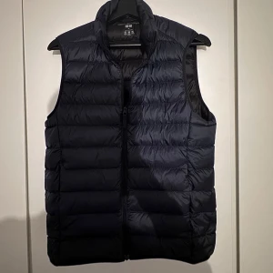 Mörkblå dunväst från Uniqlo - Säljer en stilren mörkblå dunväst från Uniqlo. Västen är i storlek xs och är knappt använd. Skick 9/10, hör gärna av er vid fler frågor.