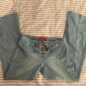 Ljusblå jeans med snörning - Snygga ljusblå jeans med unik snörning framtill. De har en bootcut-stil. Så coola säljer pga att dem inte passar❤️🥰passar både S och M