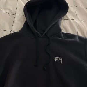 Mörkblå hoodie från Stussy - Säljer en mörkblå hoodie från Stussy med deras ikoniska logga på bröstet. Storlek S men kan passa M. 