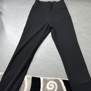 Svarta kostymbyxor från Gina Tricot - Snygga svarta kostymbyxor från Gina Tricot i storlek 34. Byxorna har en hög midja och en rak passform som ger en stilren look. Perfekta för en chic och elegant stil.