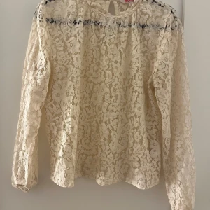Beige spetsblus från Indiska - Säljer en elegant beige spetsblus från Indiska. Blusen har långa ärmar och ett vackert spetsmönster som ger en romantisk känsla. Perfekt för att lyfta vilken outfit som helst. 💫