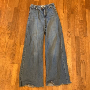 Blå jeans från Lindex - Säljer ett par blå jeans från Lindex med en vid passform. De har en klassisk femficksdesign. Perfekta för en avslappnad stil. De är avklippta 