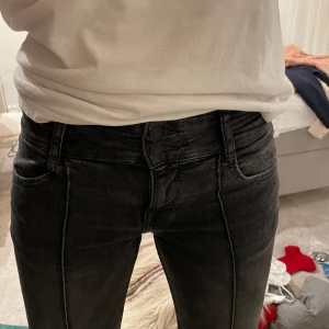 Svarta bootcut jeans från Bershka - Snygga svarta bootcut jeans från Bershka i denim. De är lågmidjade med två knappar i midjan! Använd mycket fåtal gånger! Jag har sprättat upp dem längst ner då de va korta men det går att sy tillbaka så det inte syns!💕😇De är i storlek 38 och är lite för korta för mig som är 178 cm.