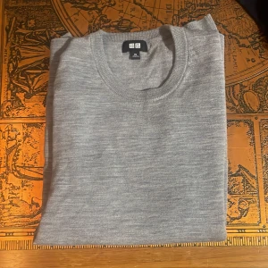 Grå merinoull tröja  - Säljer en stilren grå tröja från Uniqlo. Tröjan har en klassisk rund hals och långa ärmar, perfekt för en minimalistisk look. Passar 160-170, helt felfri. Hör av er vid frågor och funderingar!