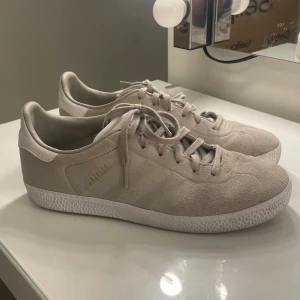 Adidas Gazelle sneakers - Gazelle skor i beige/grå med guld detaljer. Använda men ändå i fint skick. Lite märken på insidan. Kom med prisförslag!!❤️