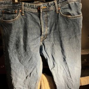 Blå jeans från Jack & Jones - Säljer ett par klassiska blå jeans från Jack & Jones i modellen Loose/Chris. De har en avslappnad passform med knappgylf och är tillverkade i bomull. Perfekta för en casual look. Fråga ifall det skulle vara något!