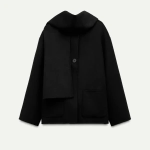 Slutsåld svart kappa med sjal- Zara - Snygg svart kappa med inbyggd sjal som ger en elegant look. Den har en enkel knäppning framtill och långa ärmar. Perfekt för kyliga dagar när du vill hålla stilen.