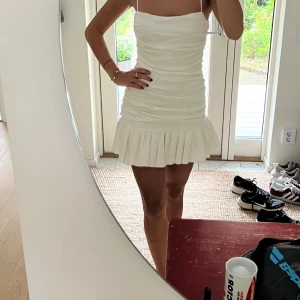 Vit klänning - Säljer en superfin vit klänning med volangdetaljer längst ner. Aldrig använd så den är mycket bra skick.