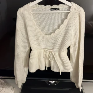 Vit stickad tröja - Superfin vit stickad tröja från Shein med volangdetaljer och knytband i midjan. Den har en v-ringad design och långa ärmar. 