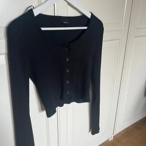 Svart långärmad tröja  - Svart långärmad tröja med knappar från Gina. Köpt storlek L då den var kortare i modellen från början, passar mig som vanligtvis har storlek S🥰  Mest hängt i garderoben. 