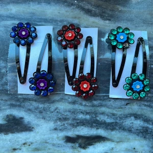 Hårklammor med blommor - Snygga hårklämmor med blommor i olika färger. Perfekt för att sätta upp håret eller som en fin detalj i håret. Totalt finns det 3 par, kan sälja det parvis eller alla tre par tillsammans. 1 par kostar 10 kr.
