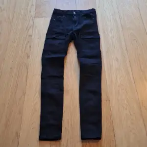 Säljer ett par svarta cargobyxor från Dr. Denim i storlek M. Byxorna har flera praktiska fickor och en snygg, tight passform. Perfekta för en casual look eller när du behöver extra förvaring. De är i mycket bra skick och redo för nya äventyr!