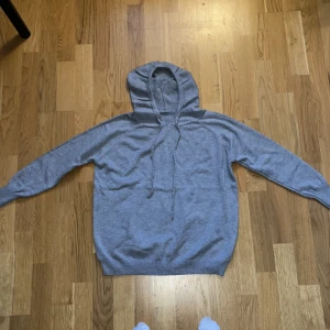 Merinoull hoodie - Säljer en enkel och bekväm grå hoodie i bra skick. Gjord på 100% merinoull. Perfekt för mysiga dagar eller en avslappnad stil. Den har en klassisk design med dragsko i huvan och ribbade muddar vid ärmslut och nederkant. Helt ny, säljes pga fel storlek. Kom med bud. Uppskattat att passa någon 170-175 - kom med prisförslag, jag är inte omöjlig. 