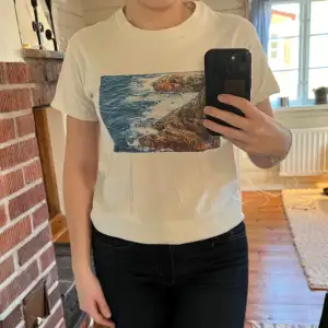 En t-shirt i tjock bomull från märket The cool elephant med ett tryck på havet                   Storlek S                                                                     På trycket syns det lite att den har blivit tvättad några gånger men annars väldigt fint skick 