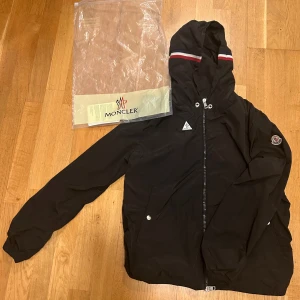 Svart Moncler Grimpeurs Windbreaker  - Säljer en snygg svart vindjacka från Moncler i Ganska bra skick, har använts flera gånger men är ren och i bra form, Dock luva snöret fattas! Size M men kan passa S.