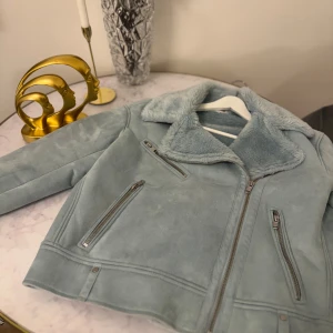 Ljusblå mockajacka  - Säljer en superfin ljusblå mockajacka med mjukt foder. Jackan har en dragkedja framtill och två fickor med dragkedjor. Perfekt för höst och vår när du vill vara både varm och stilren. Passar till både vardag och fest!