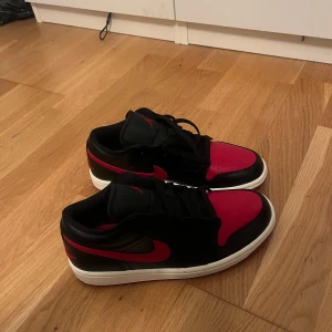 Nike Air Jordan 1 Low i svart och röd - Säljer ett par helt oanvända Nike Air Jordan 1 Low i svart och röd. Skorna är i nytt skick och säljer eftersom dom aldrig kommit till användning🤗