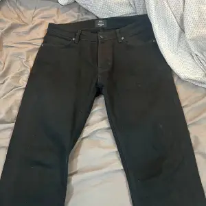 Säljer ett par svarta jeans i straight fit. De är i bra skick och har en klassisk design med fem fickor och knappgylf. Perfekta för både vardag och fest. Storlek 30:32.