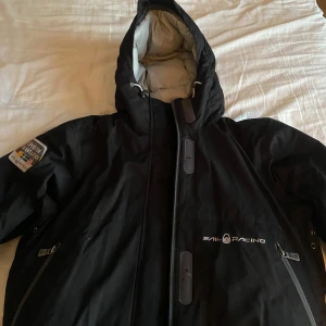 Svart jacka från Sail Racing - Säljer en jätte snygg svart jacka från Sail Racing i storlek M. Den är en lite kortare modell och mycket varm. Aldrig använd